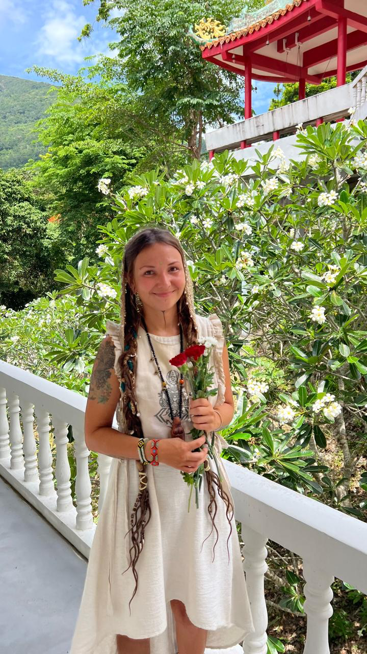 Anna holding flowers in a temple garden