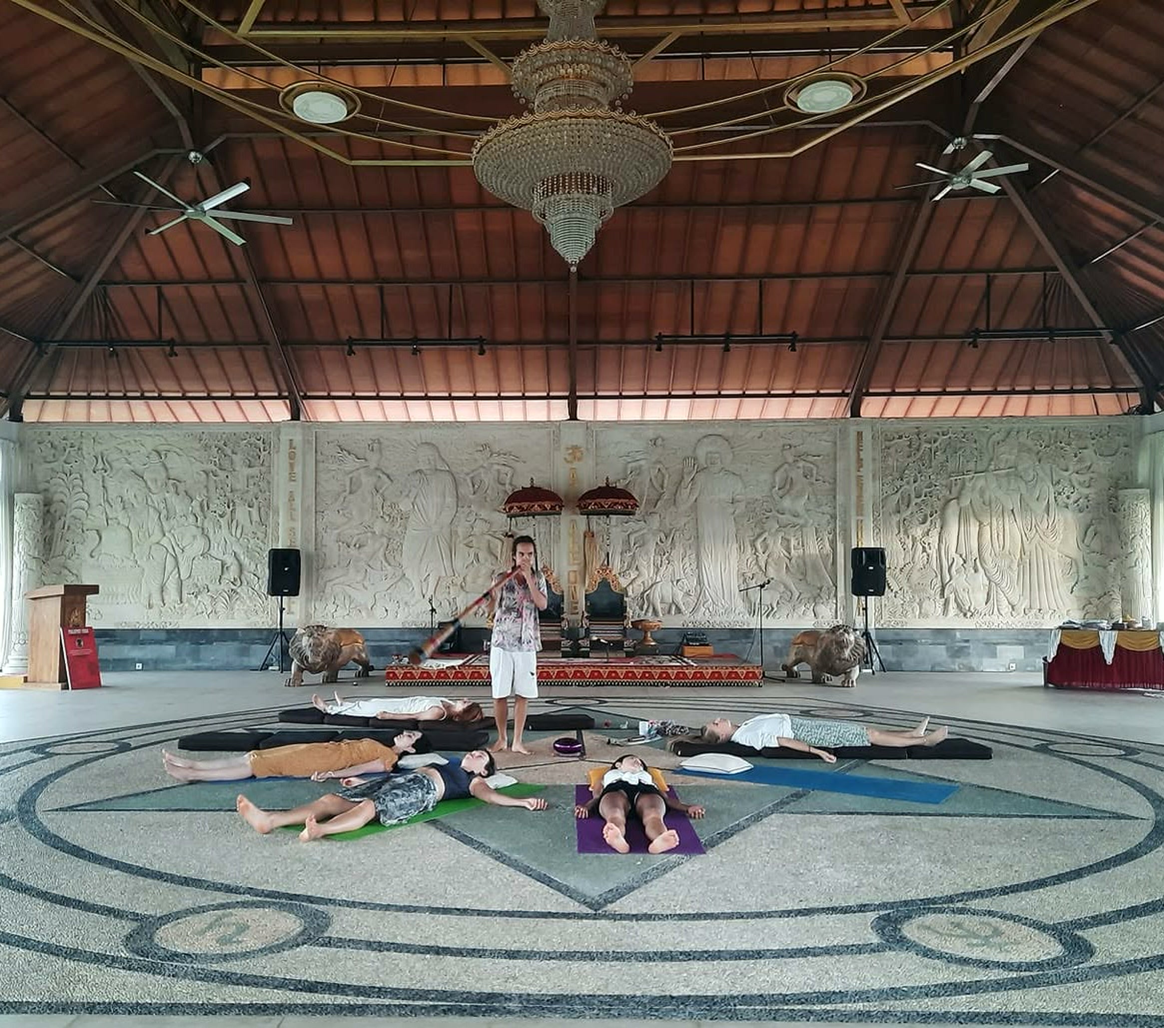 Oliv playing didgeridoo over a group lying in a temple space